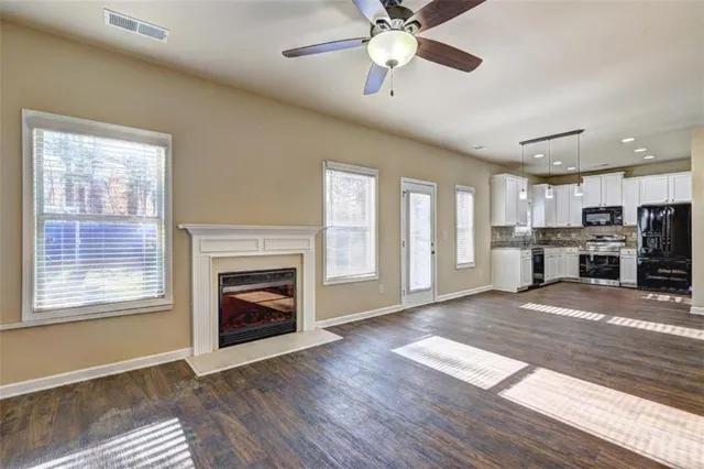 a view of an empty room with kitchen and a window