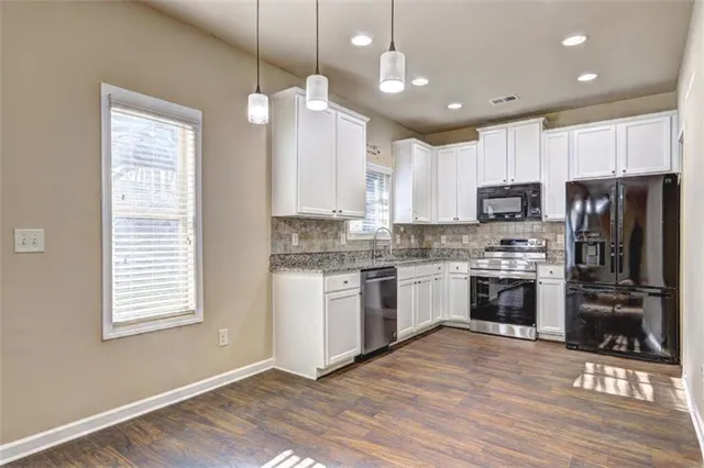 a kitchen with a refrigerator stove and wooden floor
