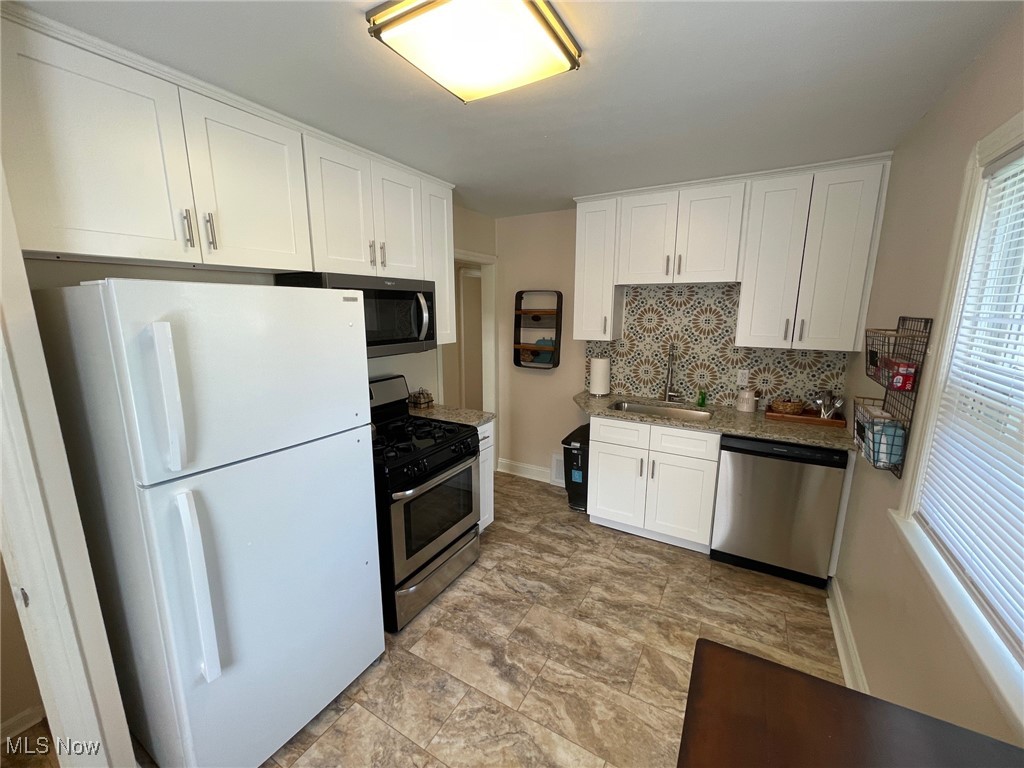 1539 Winchester Road Lyndhurst, OH 44124 - Photo 2 of 21 Kitchen featuring sink, white cabinets, decorative backsplash, and all appliances