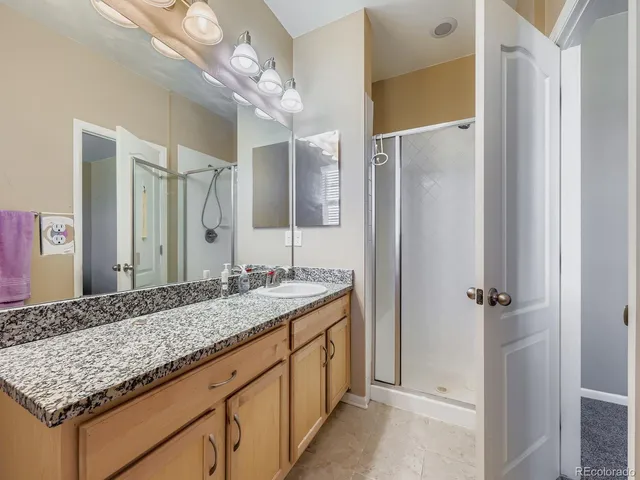 a bathroom with a granite countertop sink a mirror and shower