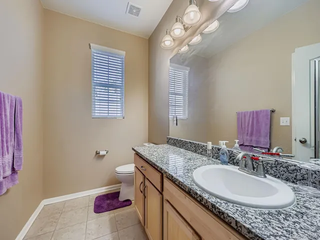 a bathroom with a granite countertop double vanity and a mirror