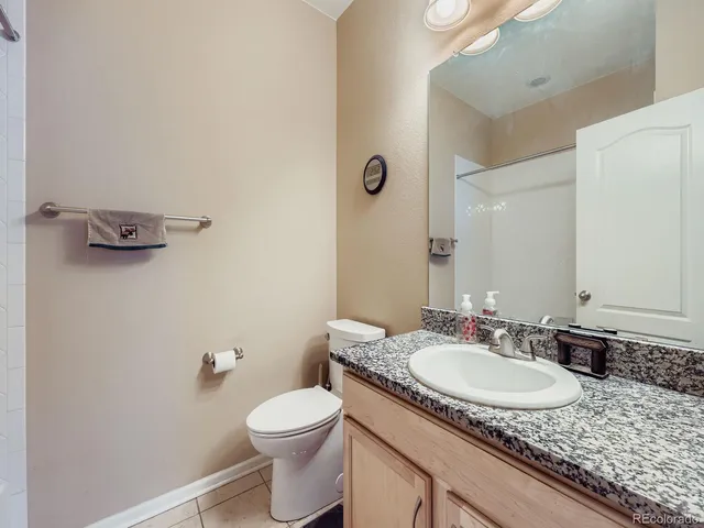 a bathroom with a granite countertop sink a toilet and a mirror