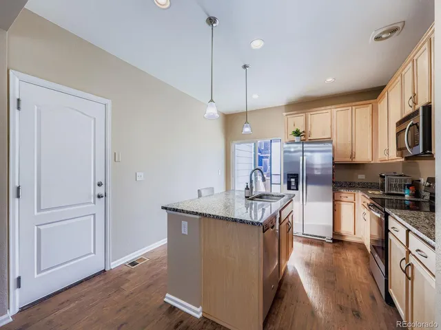 a kitchen with stainless steel appliances granite countertop a refrigerator a stove a sink and a refrigerator