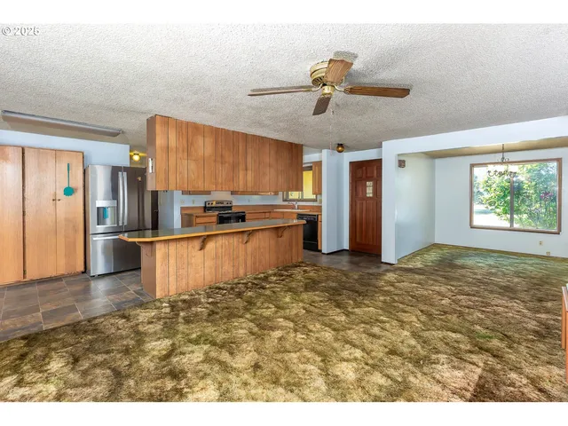 a living room with stainless steel appliances kitchen island granite countertop a refrigerator a stove top oven a sink and dishwasher