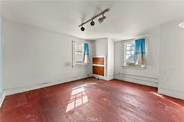 an empty room with windows and fireplace