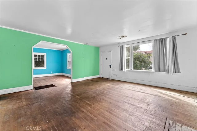 a view of an empty room with a window and wooden floor
