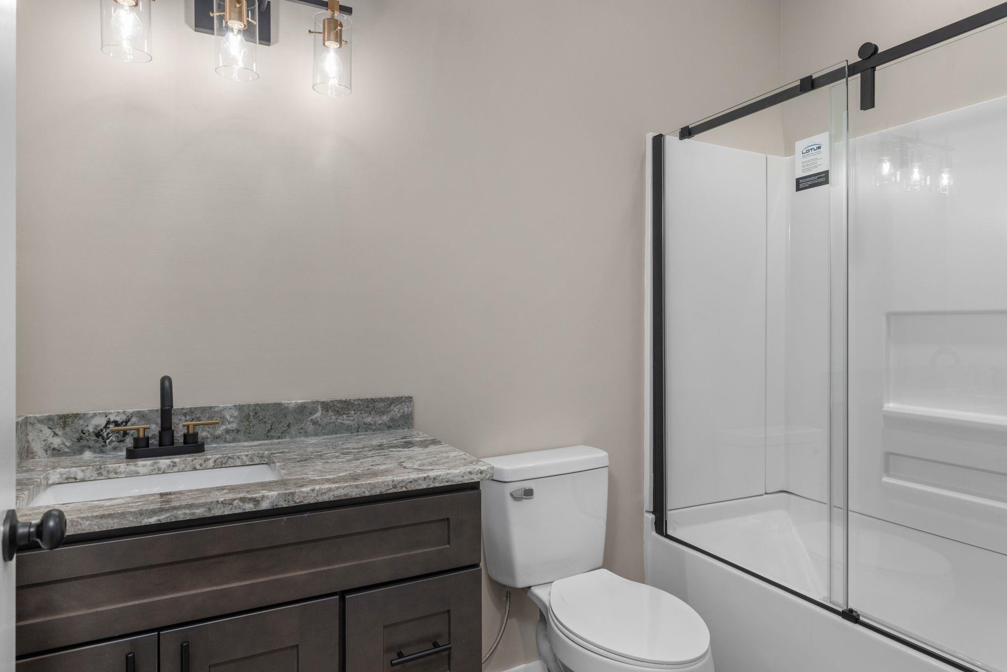 a bathroom with a granite countertop sink toilet and shower