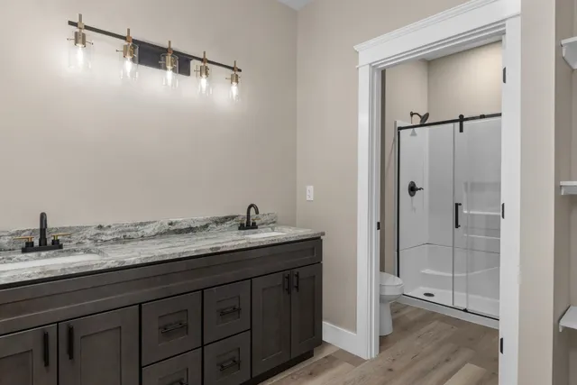 a bathroom with a granite countertop sink two mirror and shower