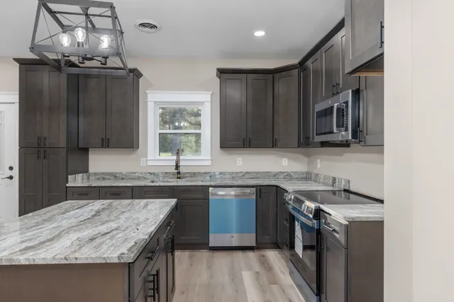 a kitchen with granite countertop a sink stove and refrigerator