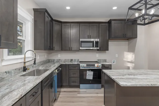 a kitchen with kitchen island granite countertop a sink stove top oven and cabinets