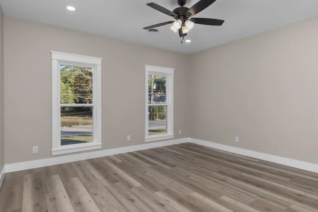 a view of an empty room with a window and wooden floor