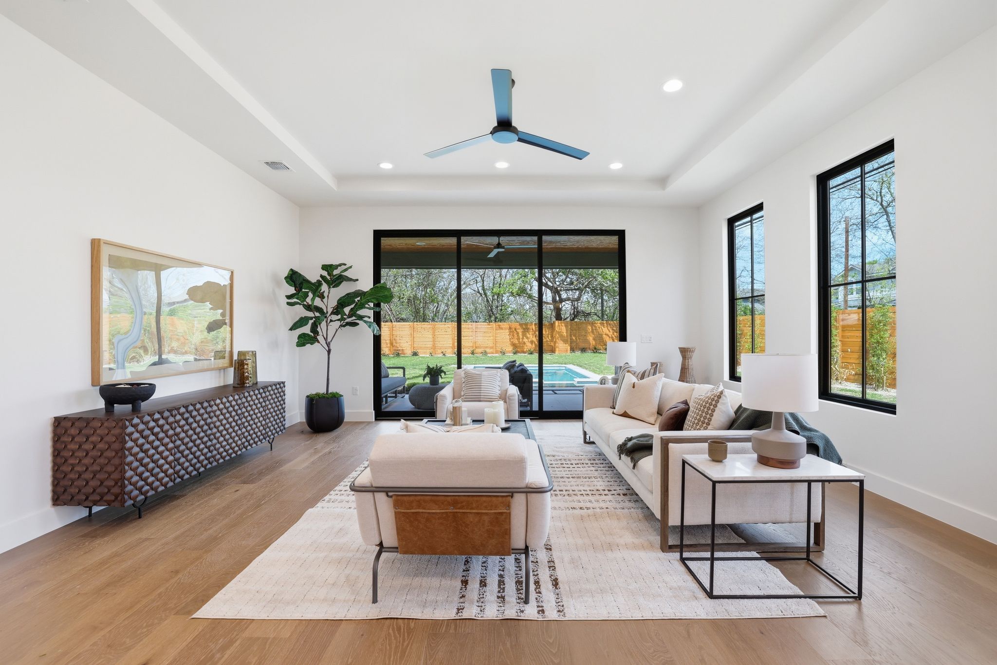 4500 Jinx Avenue Austin, TX 78745 - Photo 18 of 40 Living room featuring a ceiling fan, healthy amount of natural light, light wood-style flooring, a tray ceiling, and recessed lighting