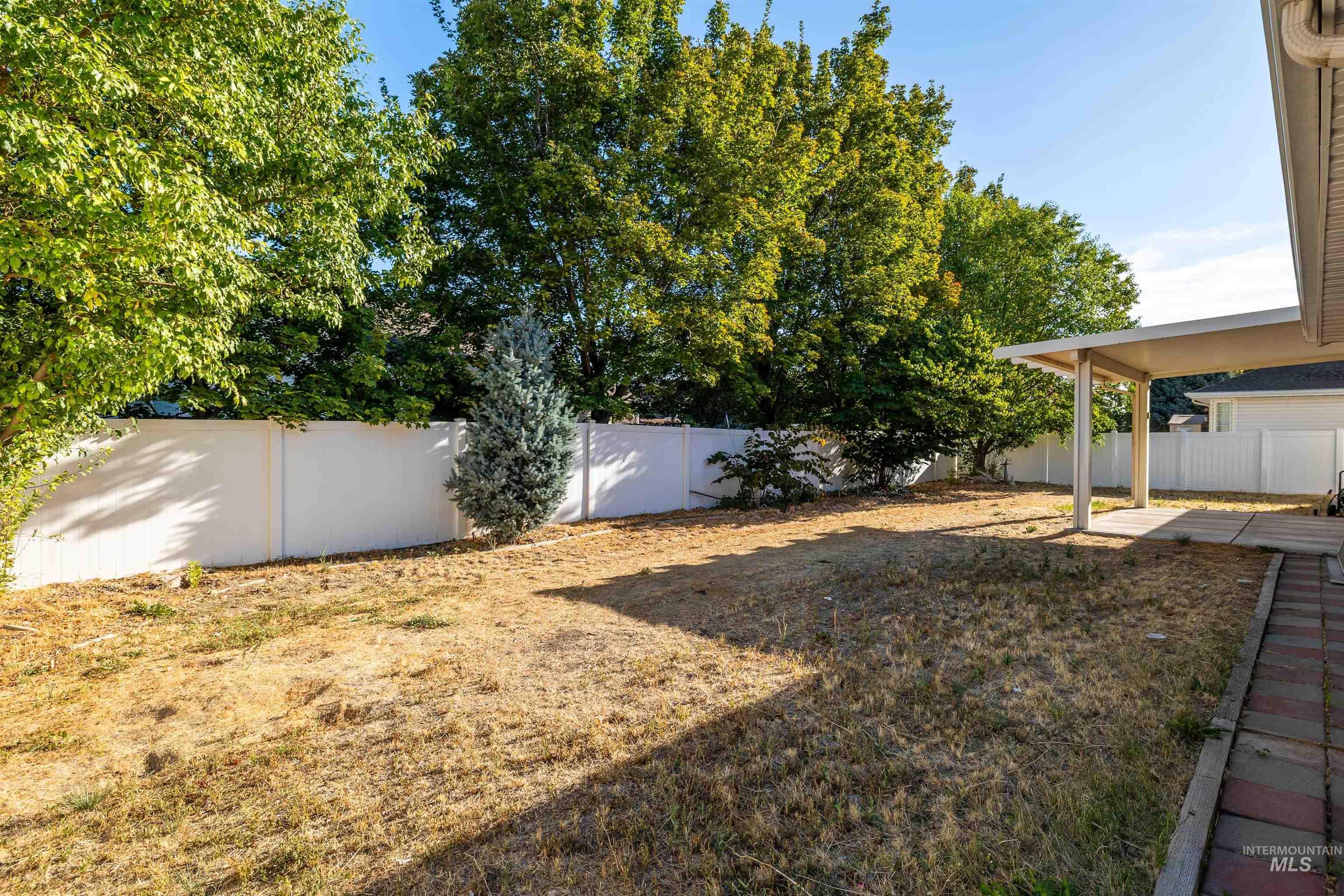 2509 Cedar Ridge Road Twin Falls, ID 83301 - Photo 25 of 36 Spacious backyard featuring a covered patio, solid privacy fencing, mature trees, and a paver walkway