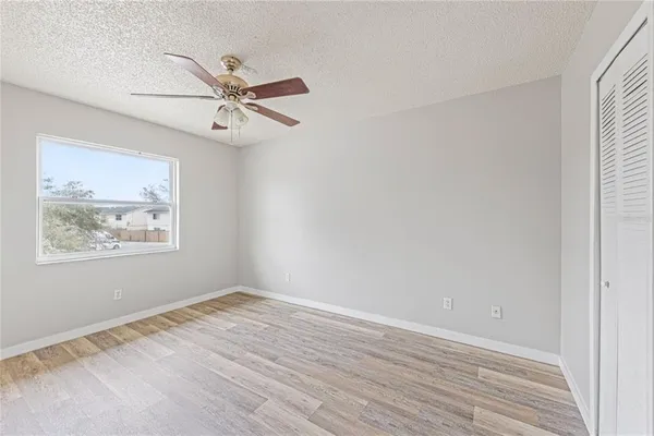 an empty room with wooden floor ceiling fan and windows