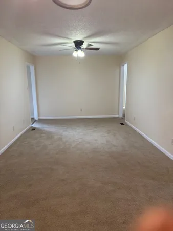 an empty room with a fan & a window