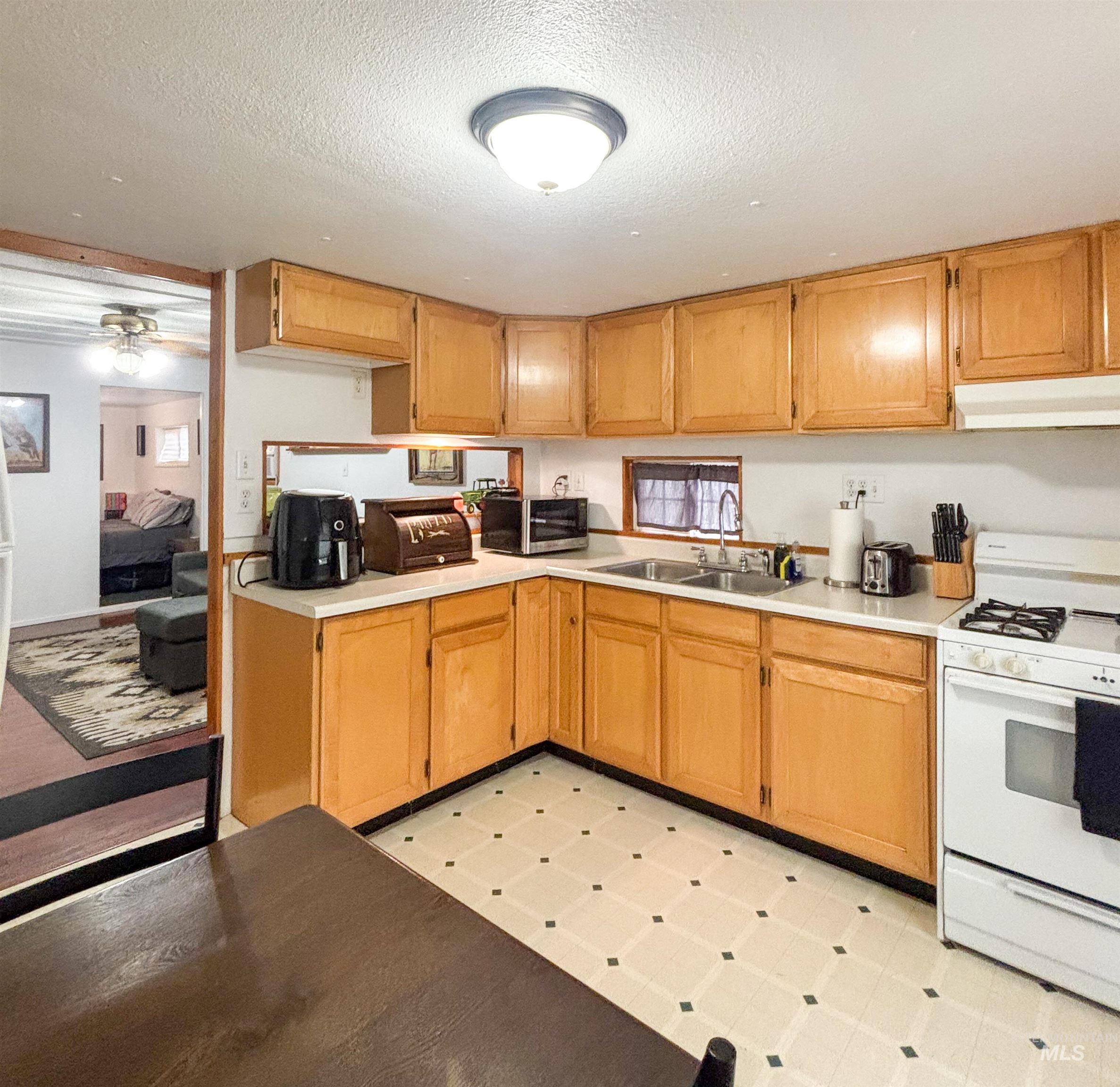 2280 Old Pullman Road, Unit 20 Moscow, ID 83843 - Photo 8 of 20 Kitchen featuring light flooring, white gas stove, a textured ceiling, light countertops, and under cabinet range hood