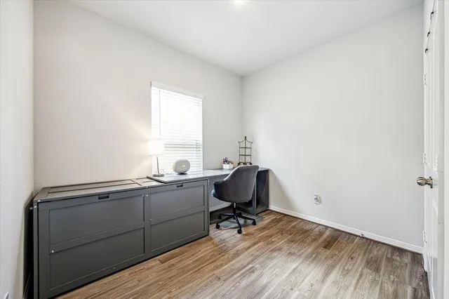 a view of a workspace with wooden floor and a window