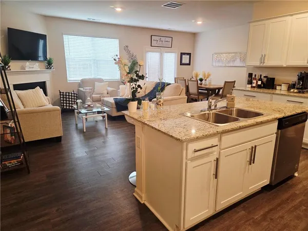 a kitchen with stainless steel appliances granite countertop a stove a sink dishwasher a refrigerator and a microwave oven with wooden floor