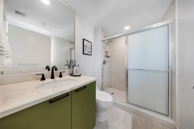 a bathroom with a sink a toilet a mirror and shower