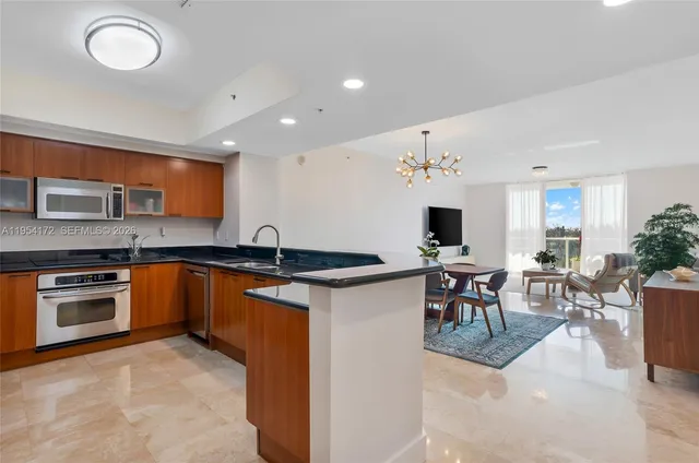 a kitchen with stainless steel appliances granite countertop a stove top oven a sink a dining table and chairs