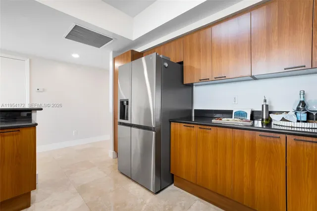 a kitchen with stainless steel appliances granite countertop a refrigerator a sink and white cabinets