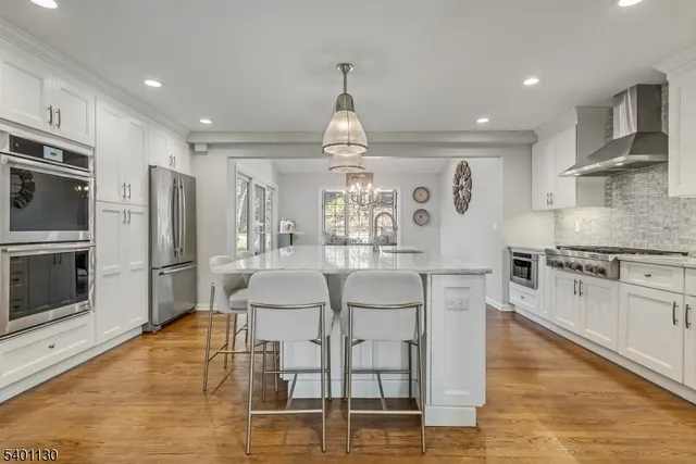 a kitchen with stainless steel appliances a dining table chairs sink and cabinets