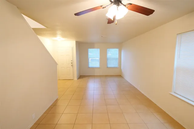 en empty room with windows and ceiling fan