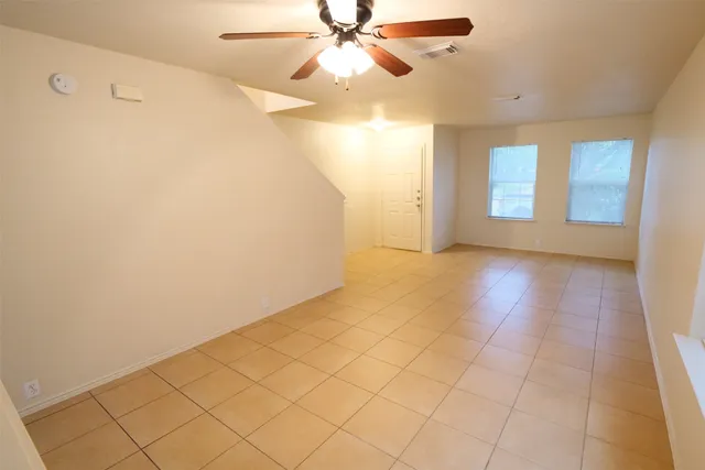 an empty room with a ceiling fan and window