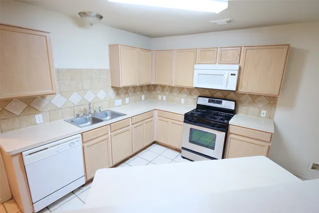 a kitchen with granite countertop a sink cabinets and stainless steel appliances