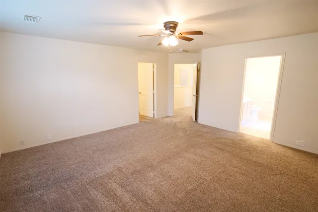 a view of an empty room with a chandelier fan