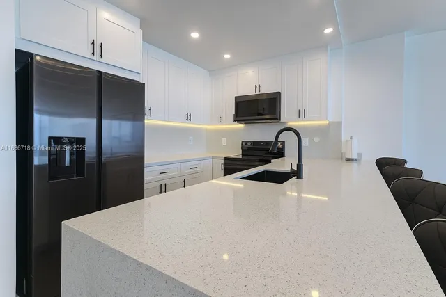 a kitchen with a refrigerator a sink a stove and chairs