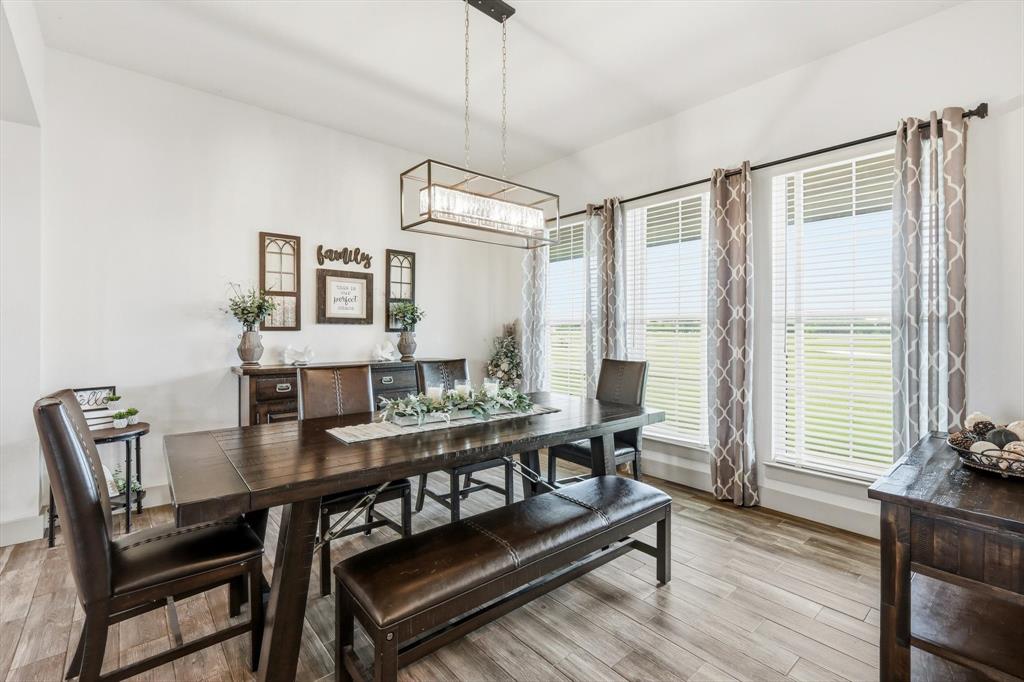 6020 Honeysuckle Road Midlothian, TX 76065 - Photo 5 of 39 Dining space featuring wood-finish flooring, a linear chandelier, and three large windows with blinds