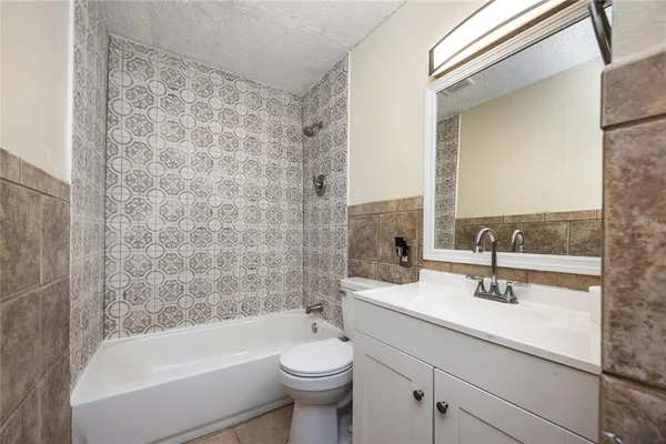 a bathroom with a granite countertop sink a toilet a mirror and bathtub