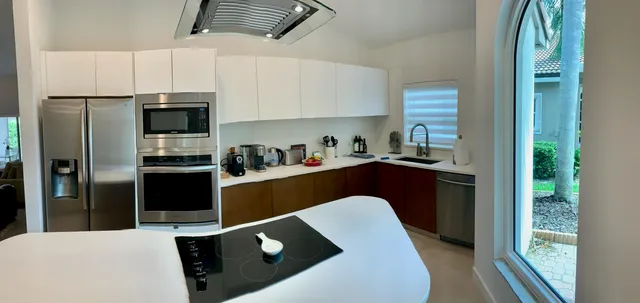 a kitchen with kitchen island a counter top space a sink and stainless steel appliances