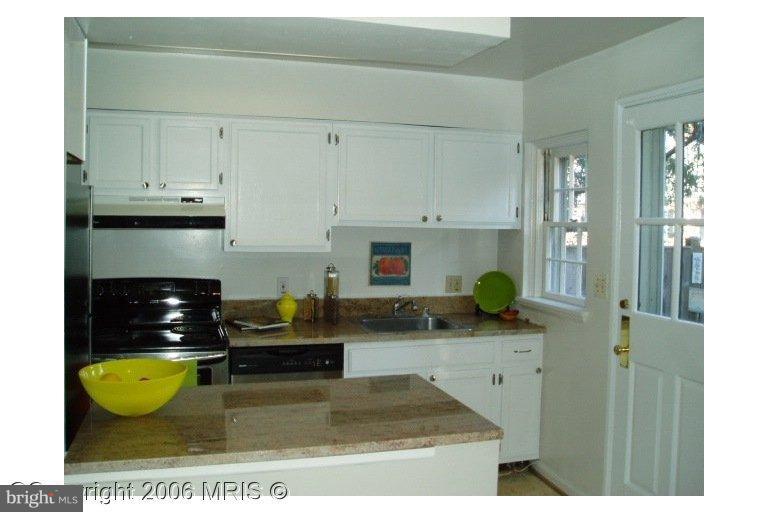 a kitchen with kitchen island granite countertop a sink a stove a counter top space and cabinets