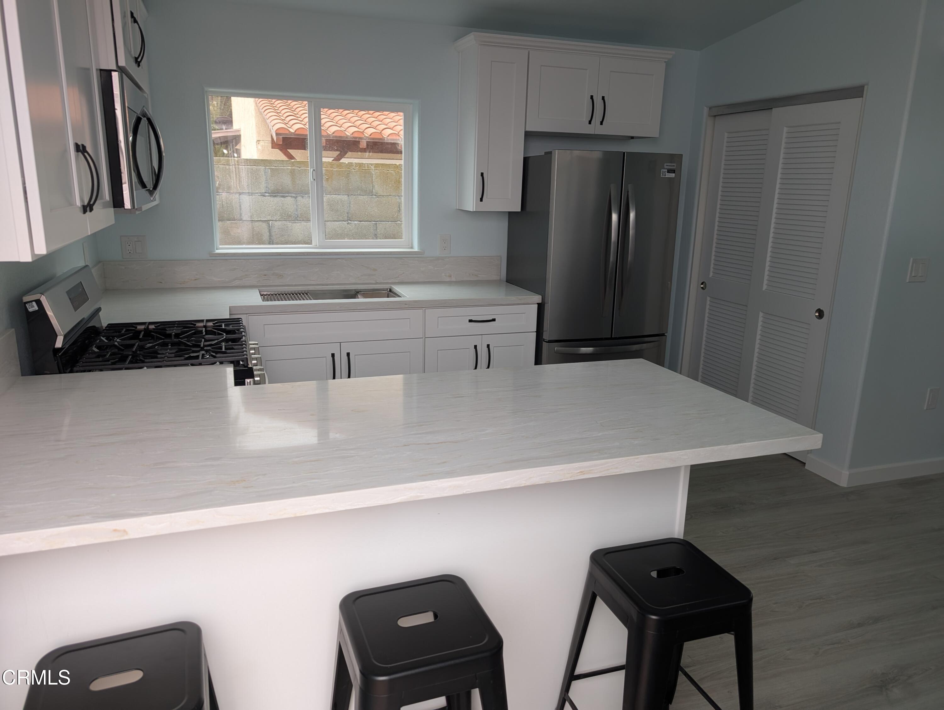 a kitchen with stainless steel appliances a sink a refrigerator and wooden cabinets