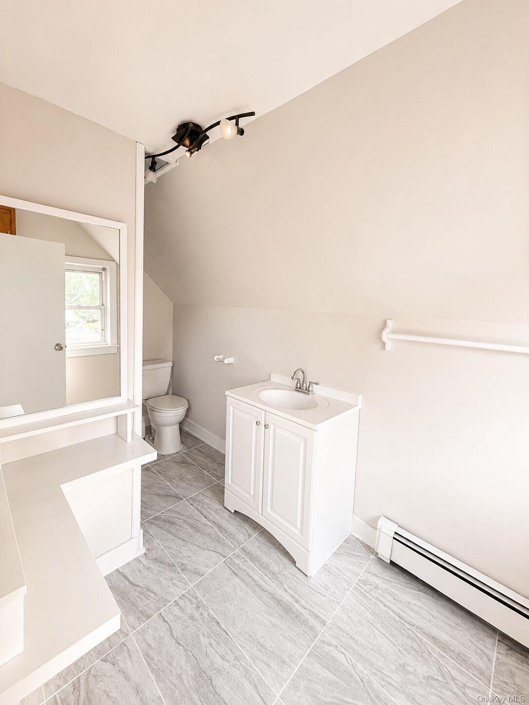 79 Division Street, Unit 3 New Rochelle, NY 10805 - Photo 13 of 17 Bathroom featuring grey tile flooring, a white vanity with an integrated sink, and track lighting.