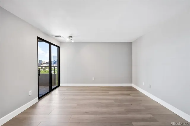 a view of an empty room with window and wooden floor