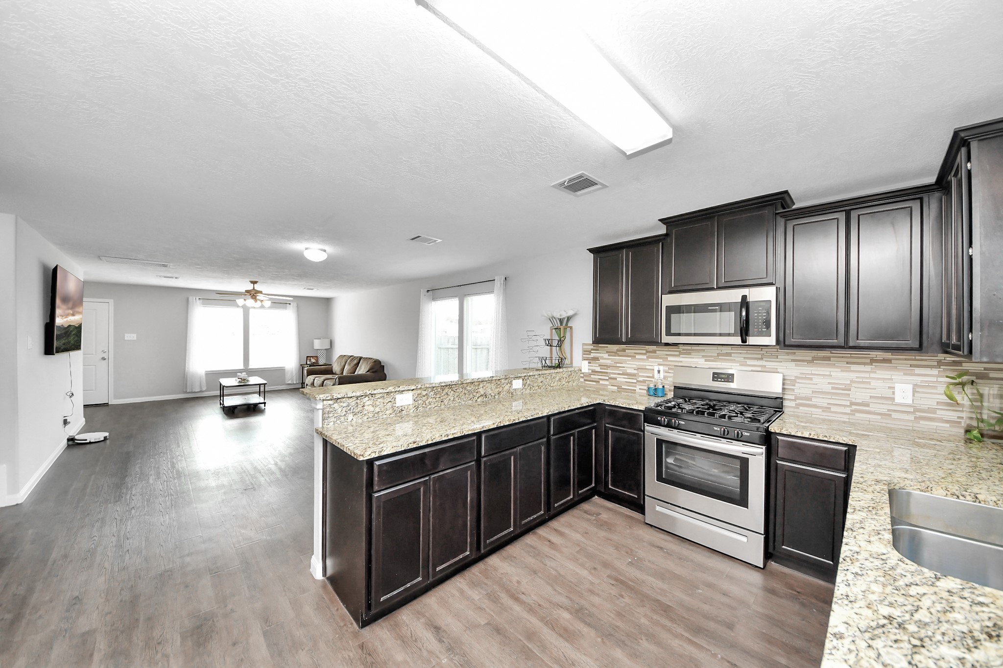 696 Road 5105 Cleveland, TX 77327 - Photo 7 of 25 a large kitchen with stainless steel appliances granite countertop a stove refrigerator and wooden floor