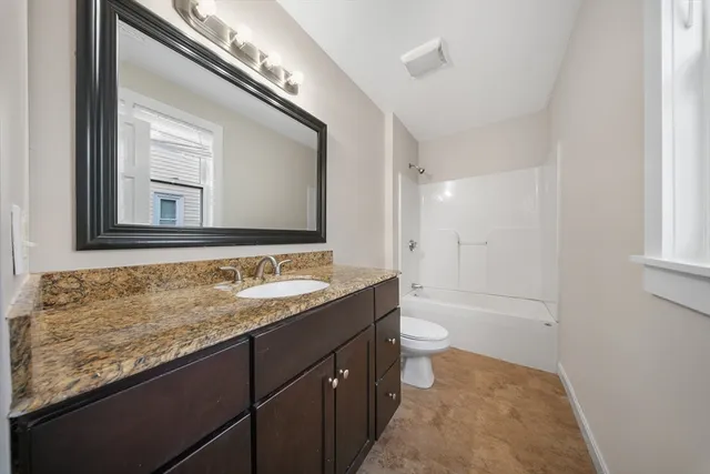 a bathroom with a granite countertop sink mirror and a bathtub