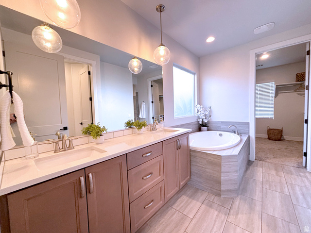 429 East Treasure Road Washington, UT 84780 - Photo 15 of 20 Bathroom featuring a built-in soaking tub, dual vanity with undermount sinks, tile flooring, and a large wall mirror