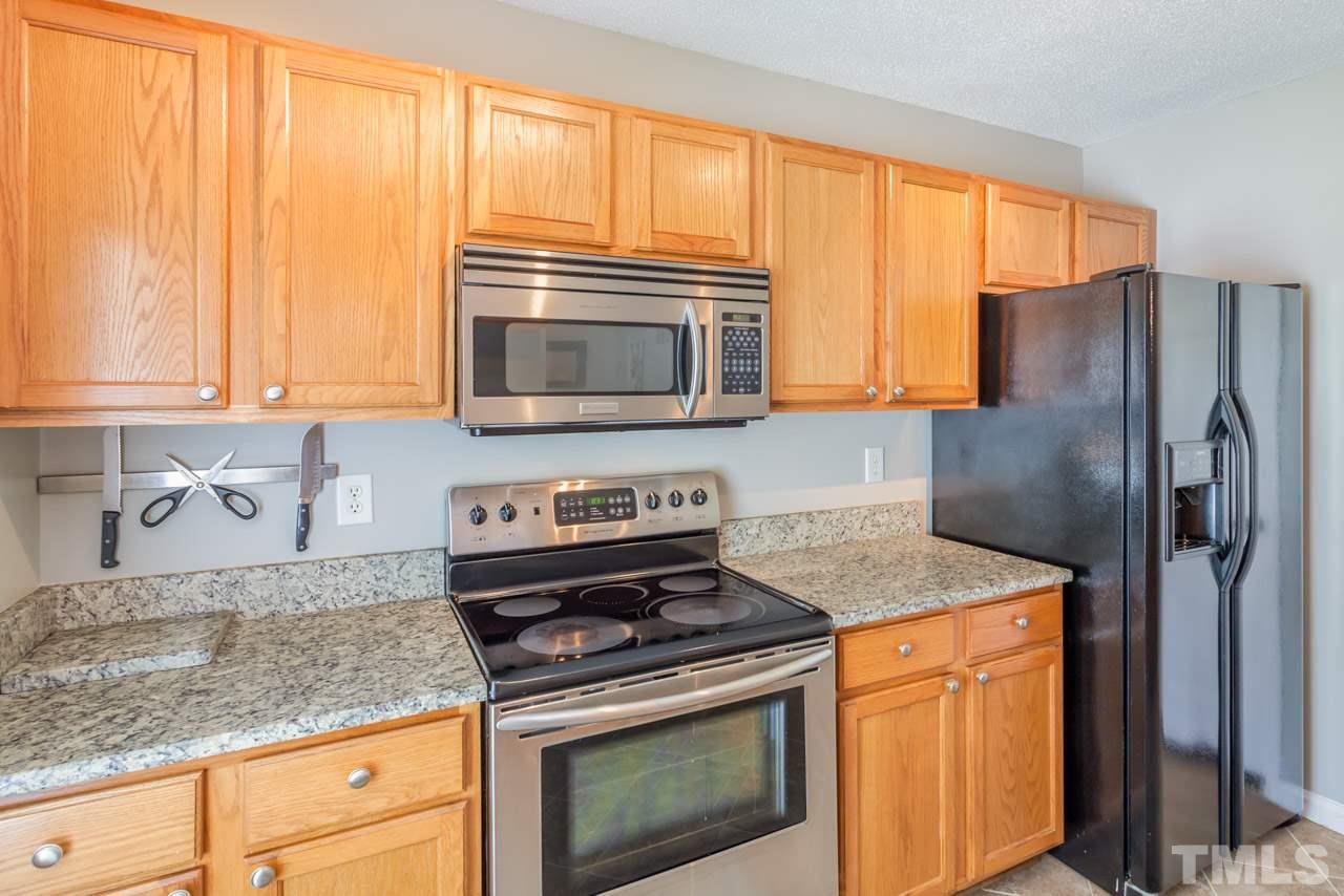 6007 Newhall Road Durham, NC 27713 - Photo 14 of 25 a kitchen with granite countertop a refrigerator stove and microwave