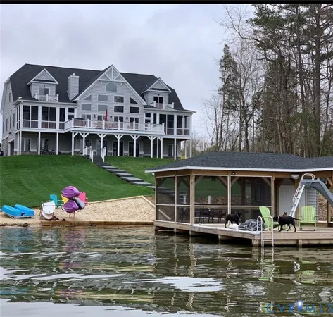 a front view of a house with a garden and lake view