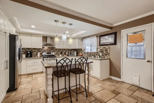 a kitchen with stainless steel appliances kitchen island granite countertop a stove a refrigerator and white cabinets with wooden floor