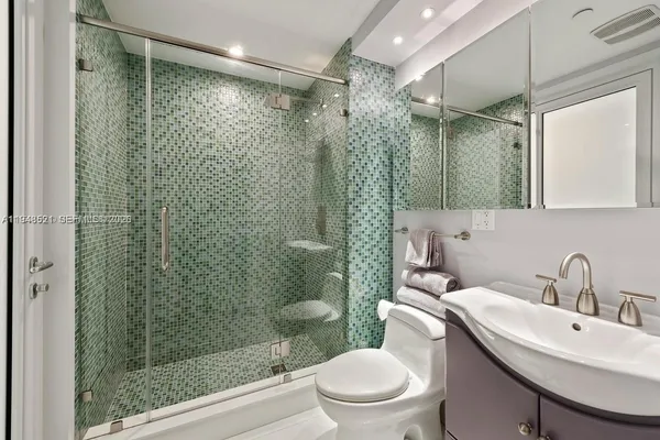 a bathroom with a shower sink vanity mirror and toilet