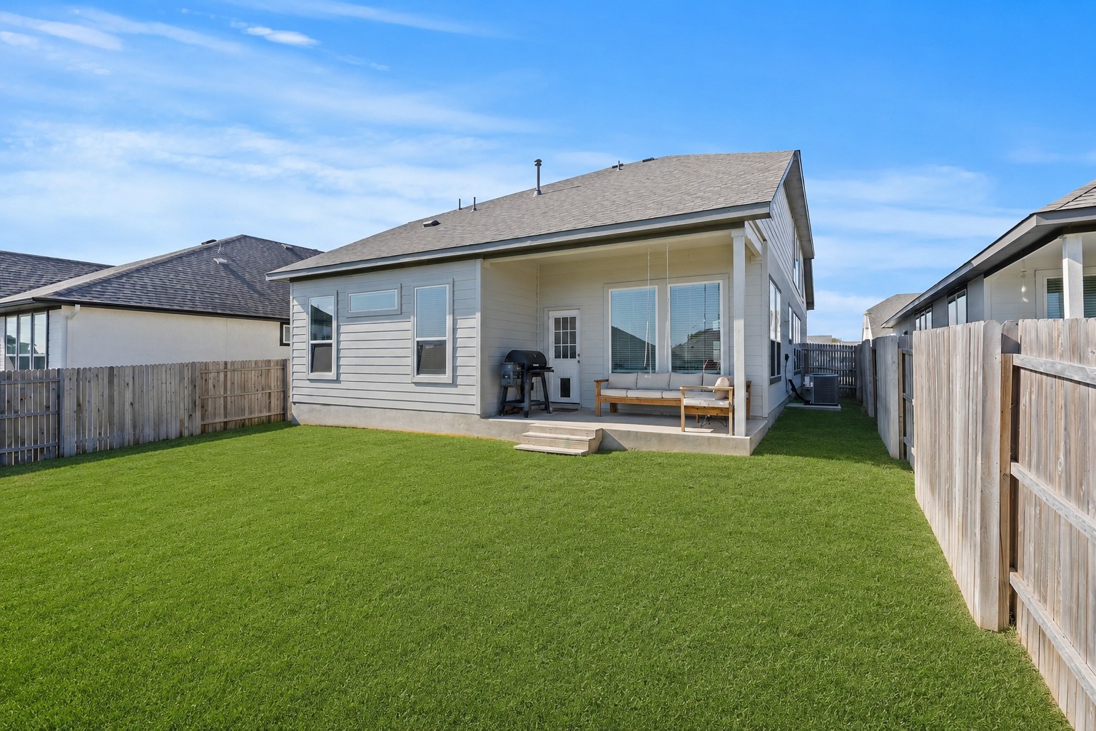 1027 Haystack New Braunfels, TX 78130 - Photo 14 of 15 A well-maintained lawn stretches to a modern home with a covered patio, ideal for outdoor leisure.