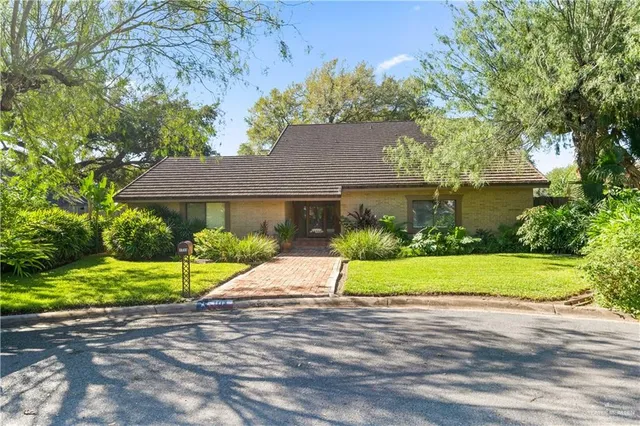 a view of yellow house with a yard and table and chairs under an umbrella