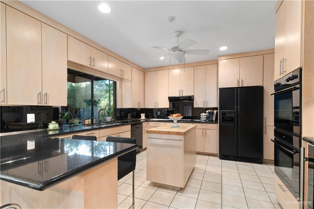 1113 Xanthisma Avenue McAllen, TX 78504 - Photo 8 of 30 Kitchen featuring light brown cabinetry, black appliances, light tile patterned floors, recessed lighting, and dark stone countertops