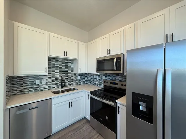 a kitchen with white cabinets and stainless steel appliances