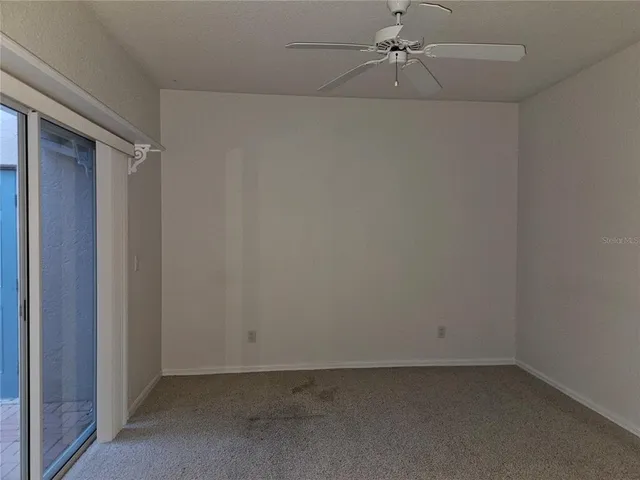 an empty room with a ceiling fan and carpet